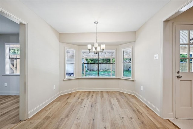 unfurnished dining area with an inviting chandelier and light hardwood / wood-style flooring