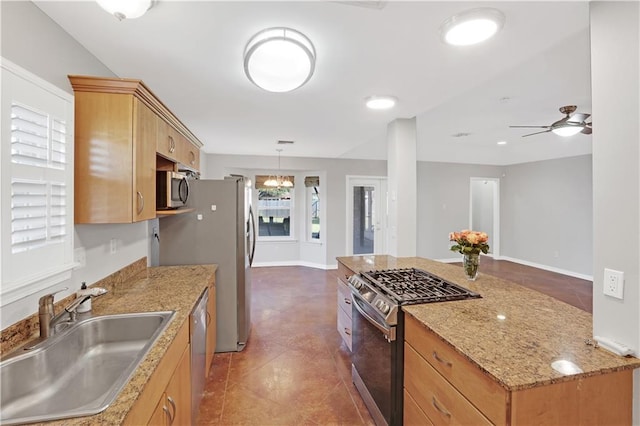 kitchen with light stone countertops, ceiling fan, sink, hanging light fixtures, and appliances with stainless steel finishes