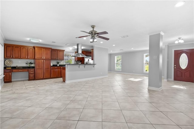 interior space featuring kitchen peninsula, ornamental molding, island range hood, ceiling fan, and stainless steel refrigerator