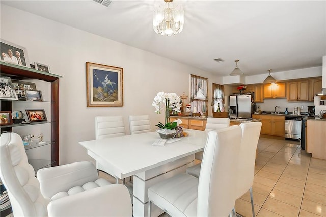 tiled dining room with sink and a chandelier