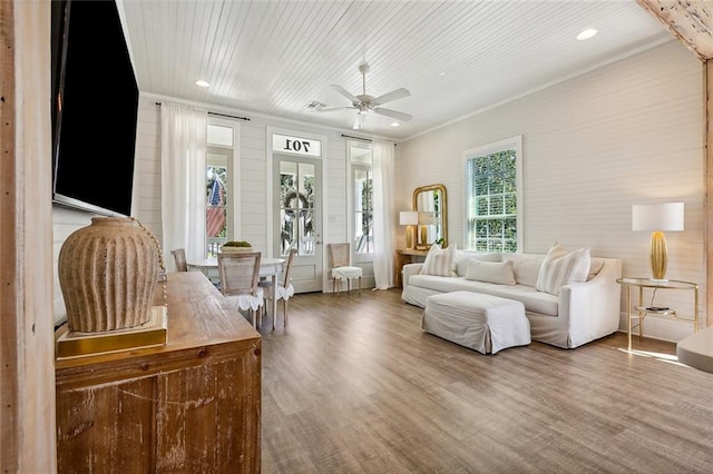 living room with wood-type flooring, ornamental molding, ceiling fan, and wooden ceiling