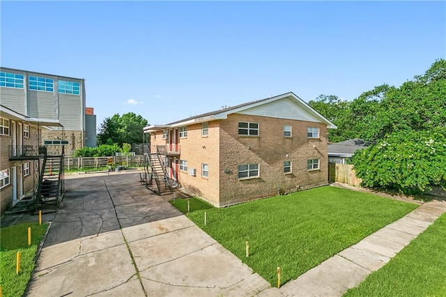 view of home's exterior featuring a yard, brick siding, stairs, and fence