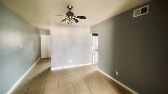 empty room featuring light tile patterned flooring, baseboards, visible vents, and ceiling fan