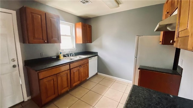 kitchen featuring brown cabinetry, visible vents, white appliances, and a sink