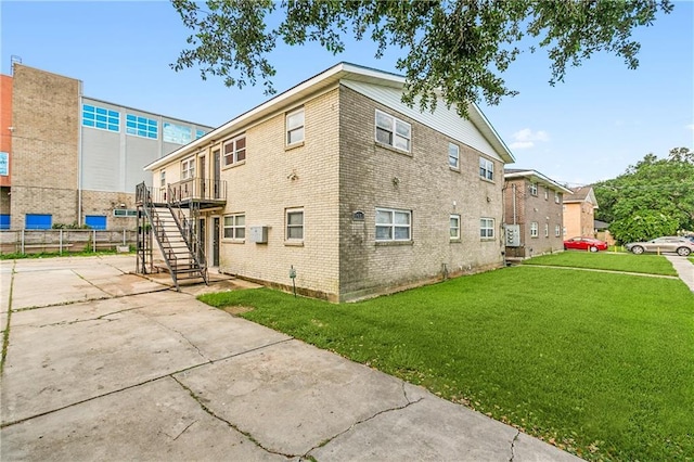 view of side of property with stairway, a lawn, and brick siding