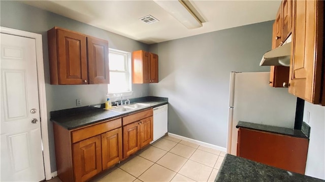 kitchen featuring dark countertops, visible vents, brown cabinets, white appliances, and a sink