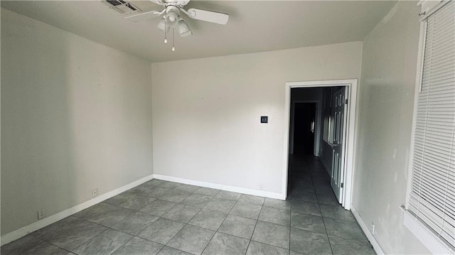 unfurnished room featuring ceiling fan and dark tile patterned floors