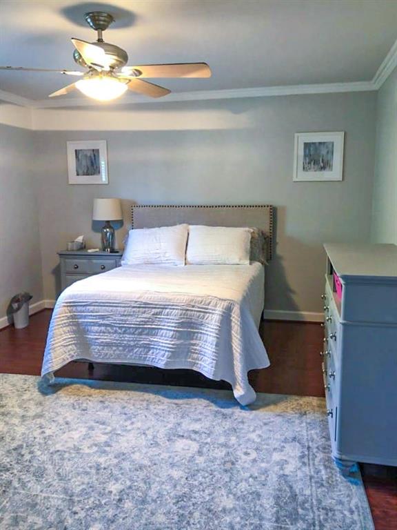 bedroom with ceiling fan, dark hardwood / wood-style floors, and ornamental molding