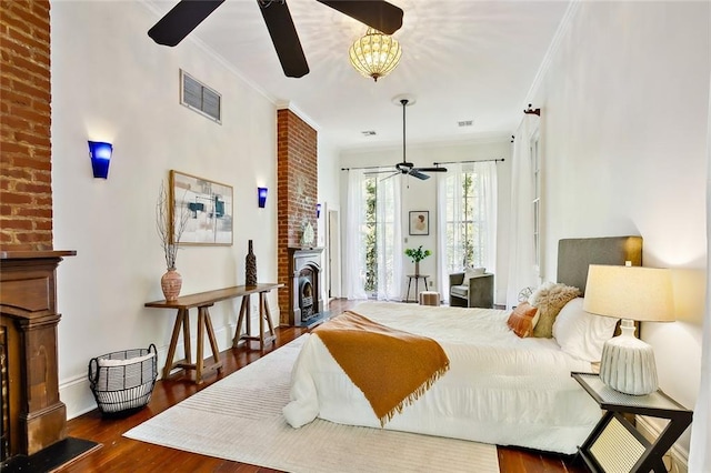 bedroom featuring ornamental molding, a fireplace, dark wood-type flooring, and ceiling fan