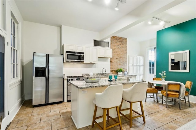 kitchen with white cabinetry, light stone countertops, appliances with stainless steel finishes, and rail lighting