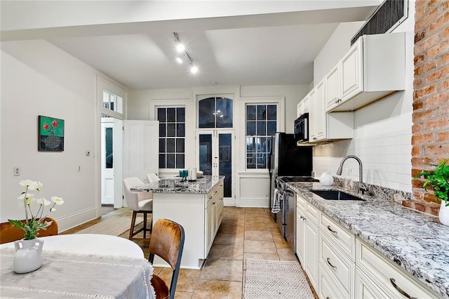 kitchen with sink, a center island, backsplash, and light stone countertops