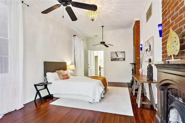 bedroom featuring dark wood-type flooring, ceiling fan, a large fireplace, and ornamental molding