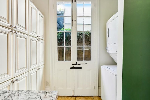 washroom featuring cabinets and stacked washer / drying machine