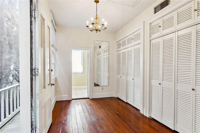 interior space featuring dark wood-type flooring, an inviting chandelier, and two closets