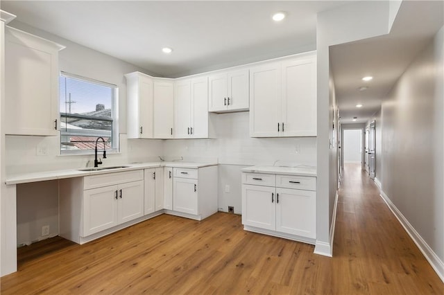 kitchen with white cabinets, light hardwood / wood-style flooring, and sink