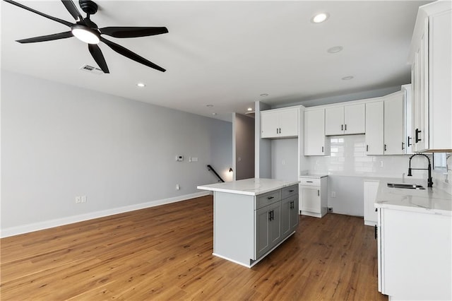 kitchen featuring wood-type flooring, white cabinets, sink, and a center island