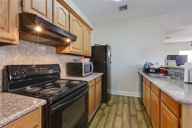 kitchen with sink, tasteful backsplash, black appliances, light stone countertops, and dark hardwood / wood-style flooring