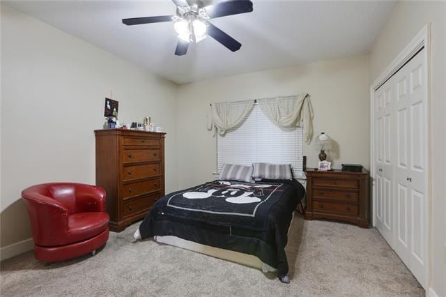 carpeted bedroom featuring a closet and ceiling fan