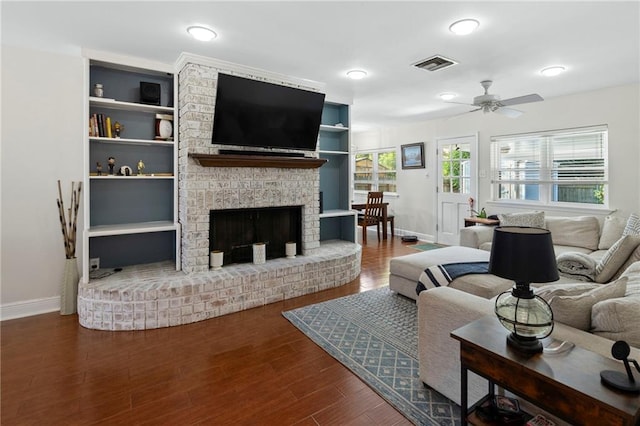 living room featuring ceiling fan, hardwood / wood-style flooring, a fireplace, and built in features