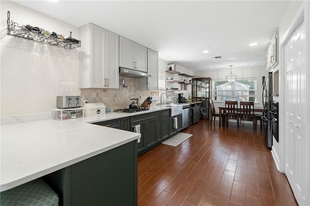 kitchen with hanging light fixtures, kitchen peninsula, sink, dark wood-type flooring, and appliances with stainless steel finishes