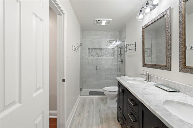 bathroom featuring wood-type flooring, a tile shower, vanity, and toilet