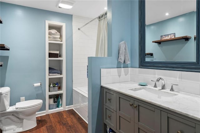 full bathroom with hardwood / wood-style floors, vanity, shower / bath combo with shower curtain, built in shelves, and toilet