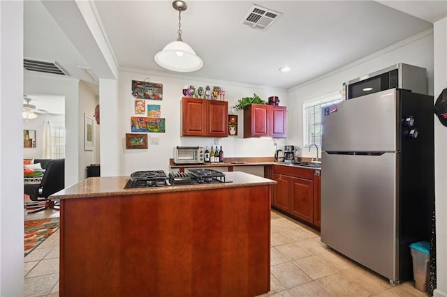 kitchen featuring ceiling fan, stainless steel appliances, sink, pendant lighting, and ornamental molding