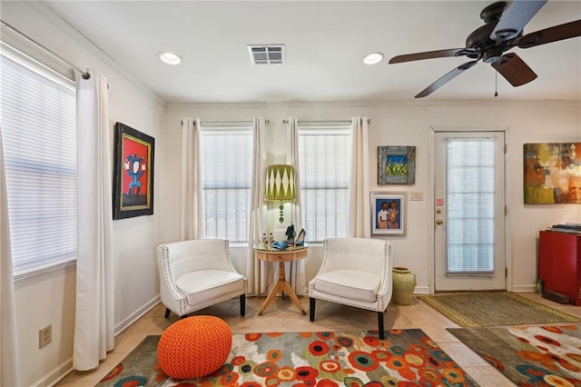 sitting room with ceiling fan, crown molding, and plenty of natural light