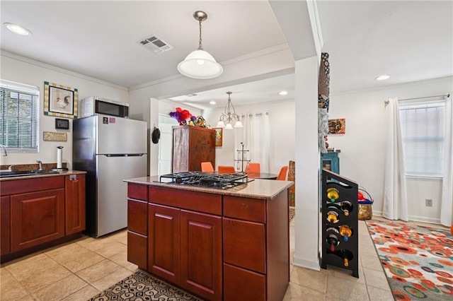 kitchen with decorative light fixtures, appliances with stainless steel finishes, a center island, an inviting chandelier, and crown molding