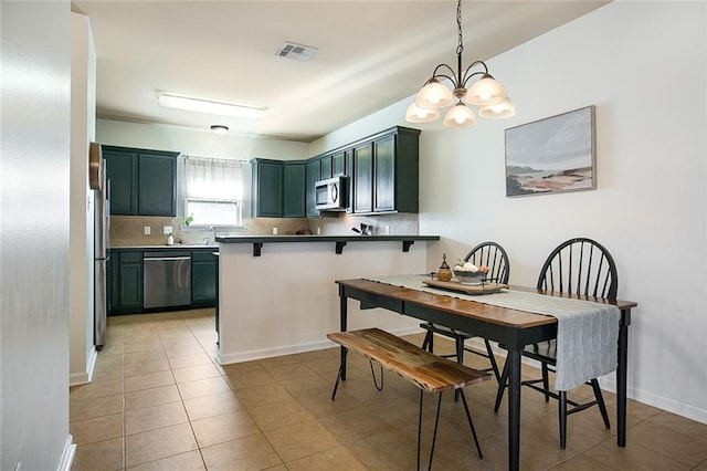 kitchen featuring tasteful backsplash, kitchen peninsula, a notable chandelier, appliances with stainless steel finishes, and decorative light fixtures