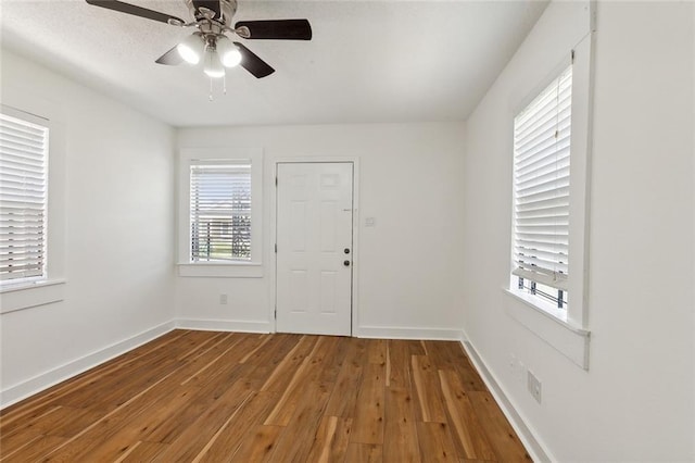 spare room with ceiling fan, a wealth of natural light, and hardwood / wood-style floors