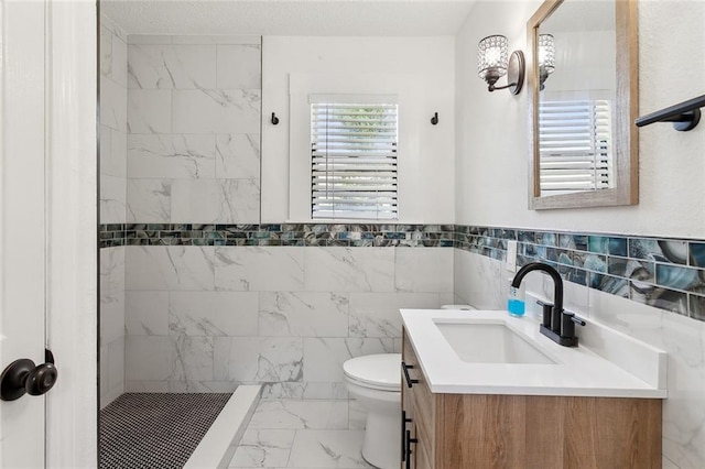 bathroom featuring tile walls, a tile shower, vanity, and toilet