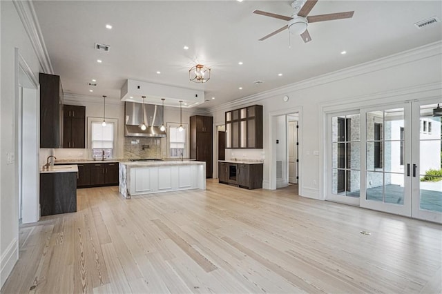 kitchen featuring light countertops, ornamental molding, exhaust hood, and visible vents