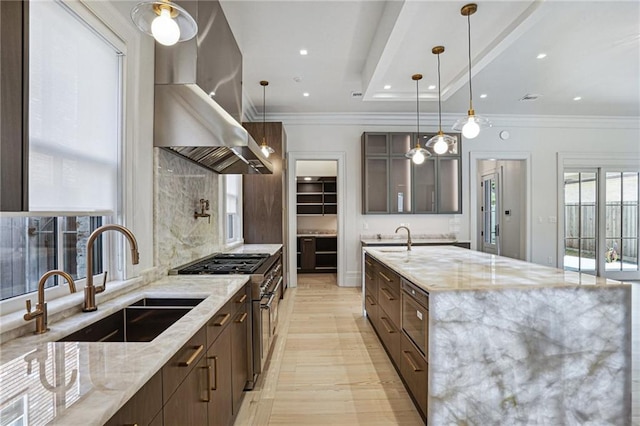 kitchen featuring light stone counters, stainless steel range, a sink, and island exhaust hood