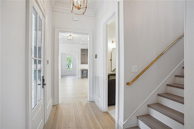 interior space with light wood finished floors, baseboards, stairway, ornamental molding, and an inviting chandelier