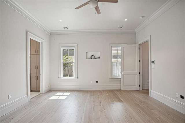 empty room with light wood-type flooring, visible vents, crown molding, and baseboards