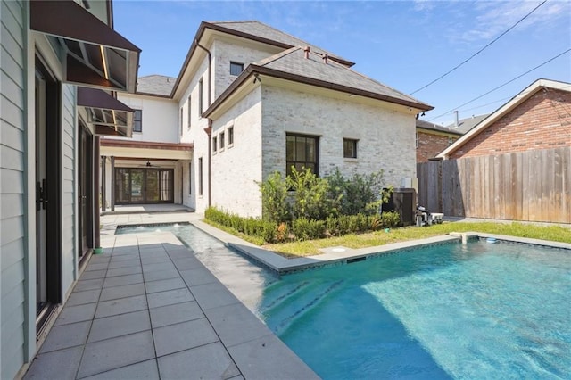 pool with a patio area, fence, and cooling unit