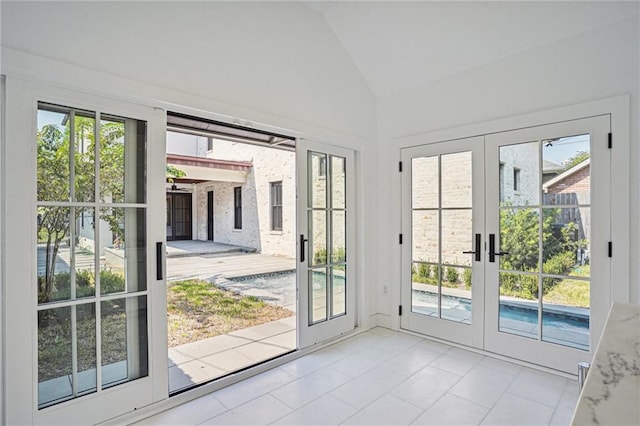 entryway featuring lofted ceiling, french doors, and light tile patterned floors