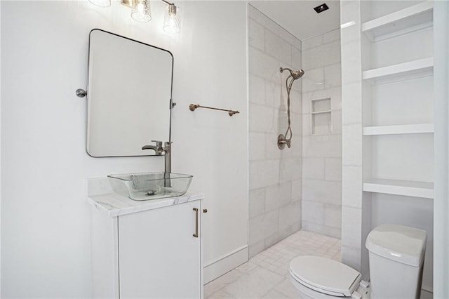 bathroom featuring a tile shower, vanity, built in features, and toilet