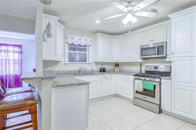 kitchen with a breakfast bar area, sink, stainless steel appliances, kitchen peninsula, and white cabinets