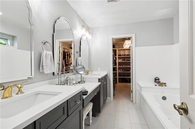 bathroom with a bathtub, tile patterned flooring, vanity, and a textured ceiling