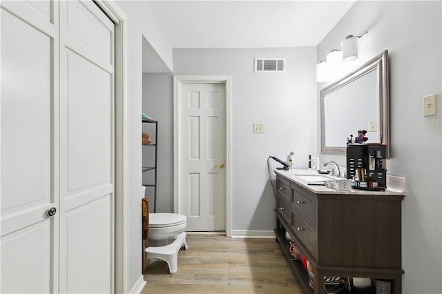 bathroom with hardwood / wood-style floors, vanity, and toilet