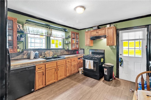 kitchen featuring black appliances, tile counters, sink, and light hardwood / wood-style floors