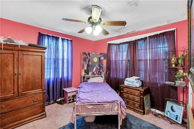 carpeted bedroom featuring ceiling fan and a textured ceiling