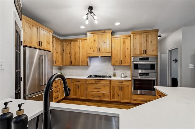 kitchen featuring an inviting chandelier, decorative backsplash, sink, and stainless steel appliances