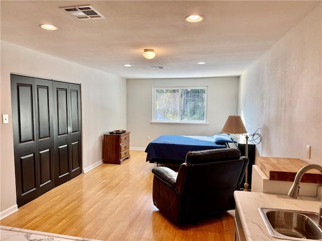 bedroom with a closet, light hardwood / wood-style flooring, and sink