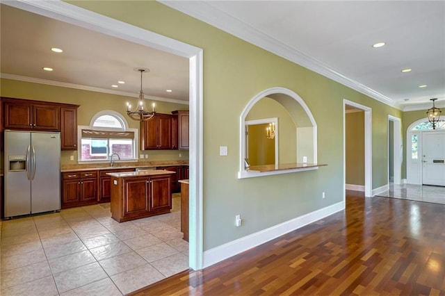 kitchen with an inviting chandelier, stainless steel fridge, light wood-type flooring, crown molding, and hanging light fixtures