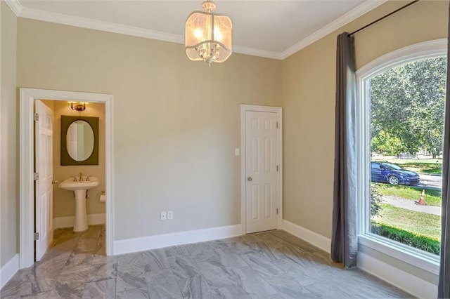 unfurnished room with a notable chandelier, ornamental molding, and sink