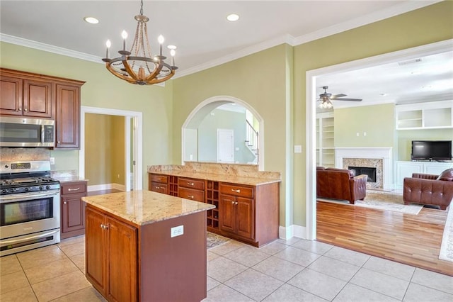 kitchen with built in features, appliances with stainless steel finishes, a kitchen island, and light tile patterned floors