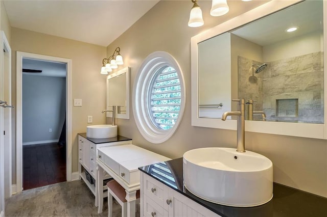 bathroom with tiled shower, vanity, and wood-type flooring